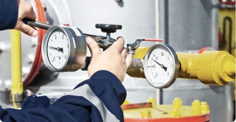 Worker checking pressure gauges on a fuel valve train during a combustion leak test.