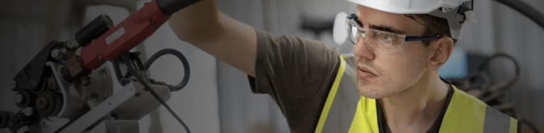 Machinist wearing required PPE at a metal lathe during a machine safeguarding assessment.